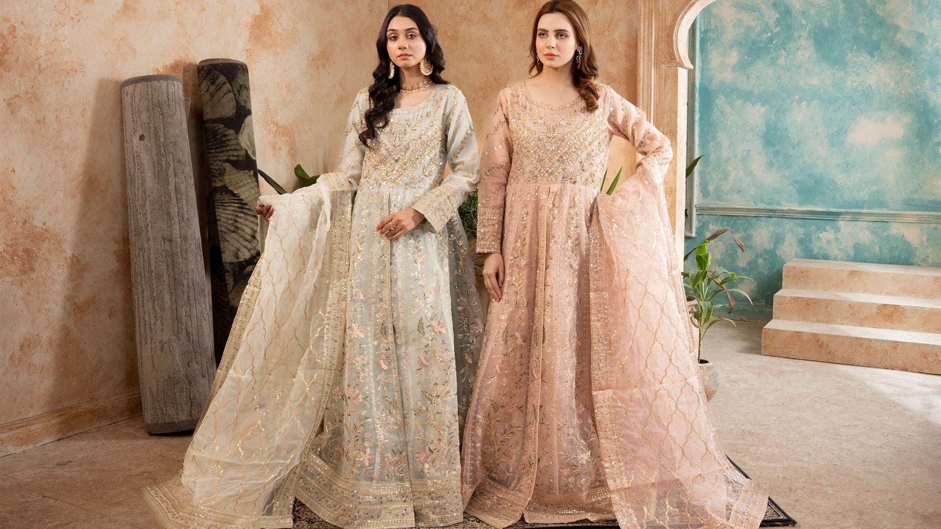 Two women in elegant dresses standing in a decorative room.